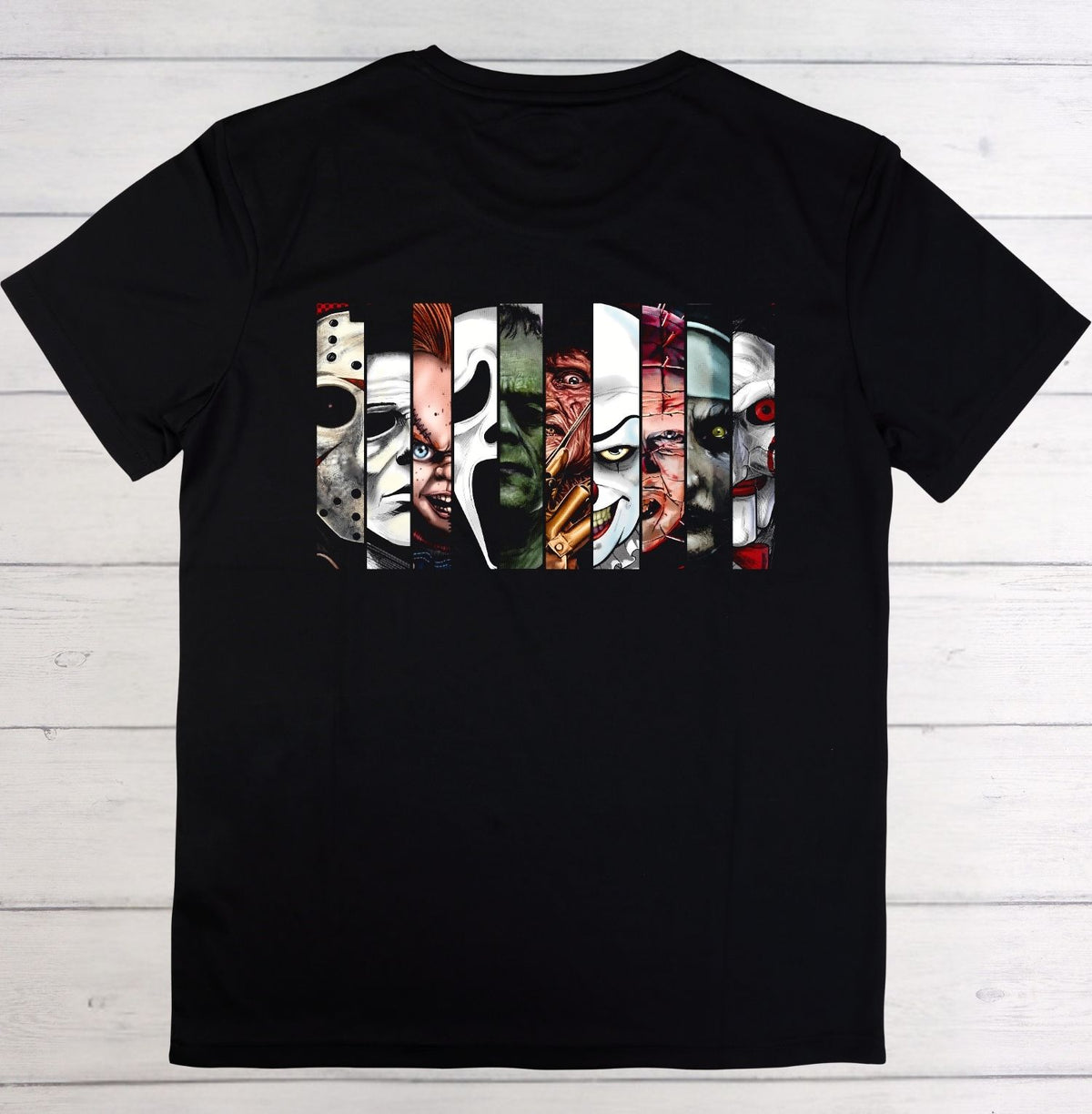 A black short-sleeve t-shirt laid flat on a white wood plank background, featuring a large graphic print of horror movie villains' faces.
