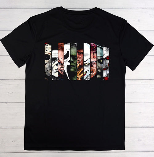 A black short-sleeve t-shirt laid flat on a white wood plank background, featuring a large graphic print of horror movie villains' faces.