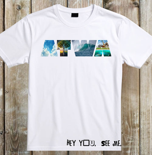 A white short-sleeve t-shirt laid flat on a rustic wooden plank background. The chest features a graphic spelling 'HAWA' where each letter is filled with a tropical scene (clouds, palm tree, ocean wave, beach, lighthouse).