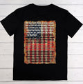 Black t-shirt with American flag design and text on a wooden surface
