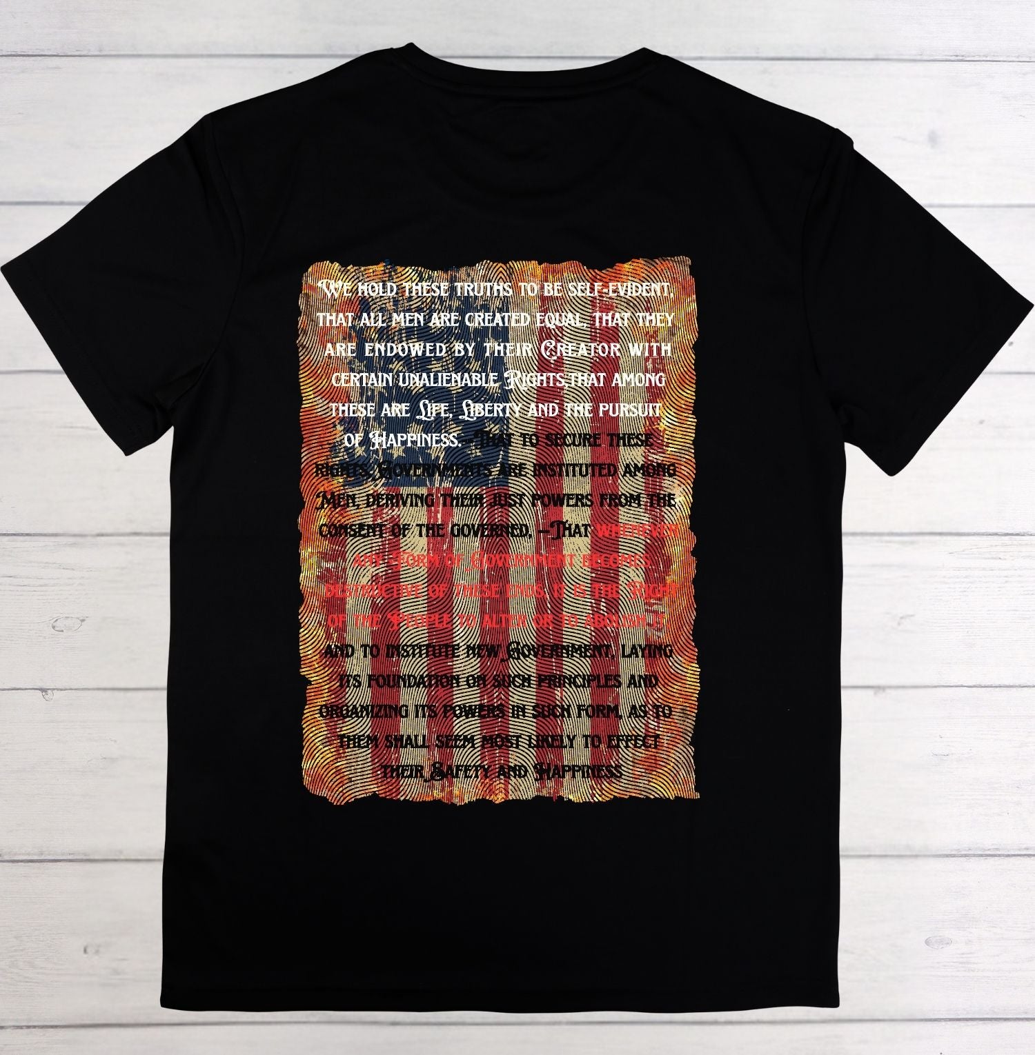 Black t-shirt with American flag design and text on a wooden surface
