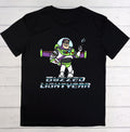 A black short-sleeve crewneck t-shirt featuring a graphic of Buzz Lightyear with the text 'BUZZED LIGHTYEAR' underneath, displayed flat against a light gray wood plank background.