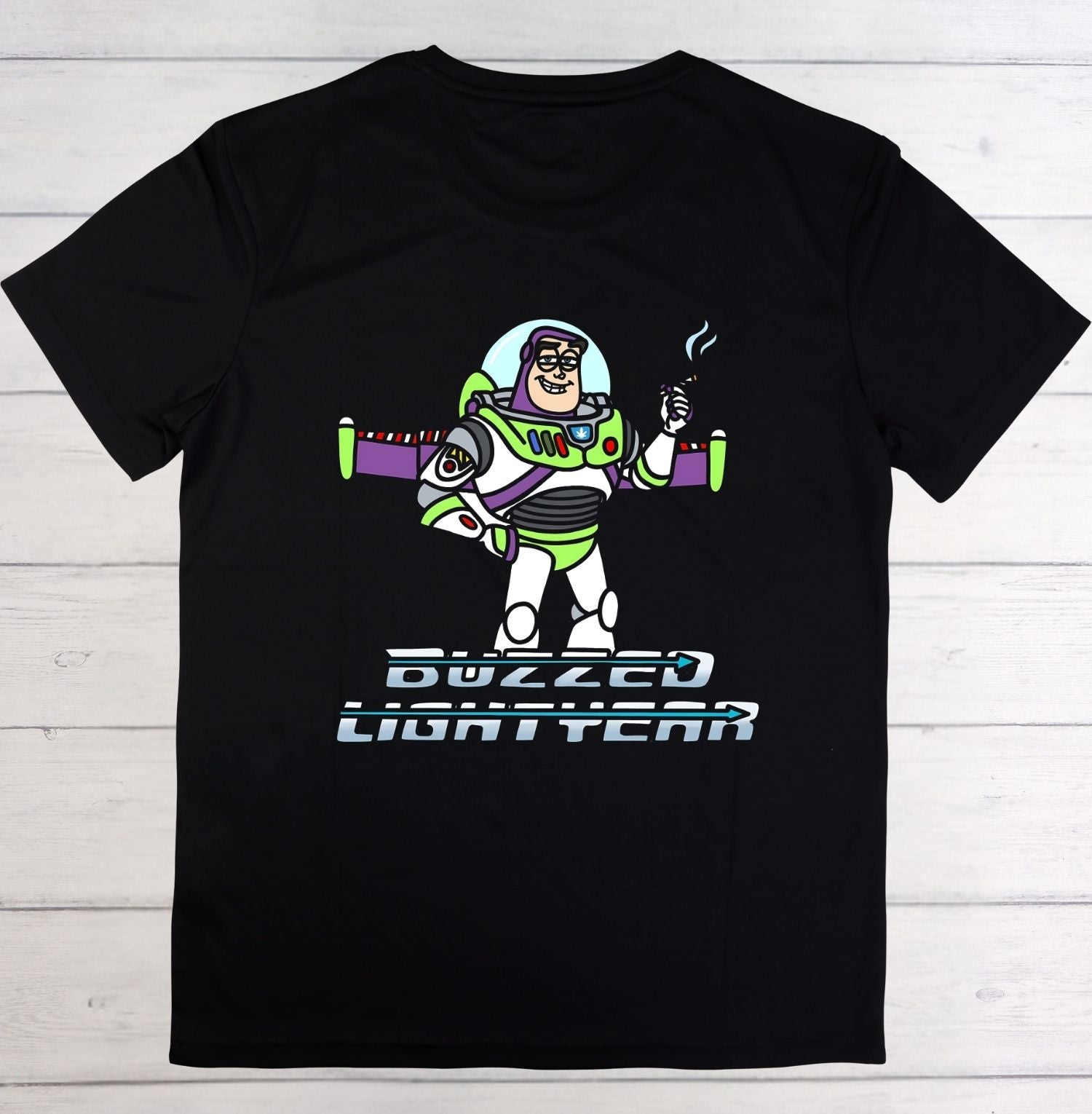 A black short-sleeve crewneck t-shirt featuring a graphic of Buzz Lightyear with the text 'BUZZED LIGHTYEAR' underneath, displayed flat against a light gray wood plank background.