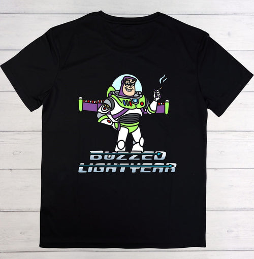 A black short-sleeve crewneck t-shirt featuring a graphic of Buzz Lightyear with the text 'BUZZED LIGHTYEAR' underneath, displayed flat against a light gray wood plank background.