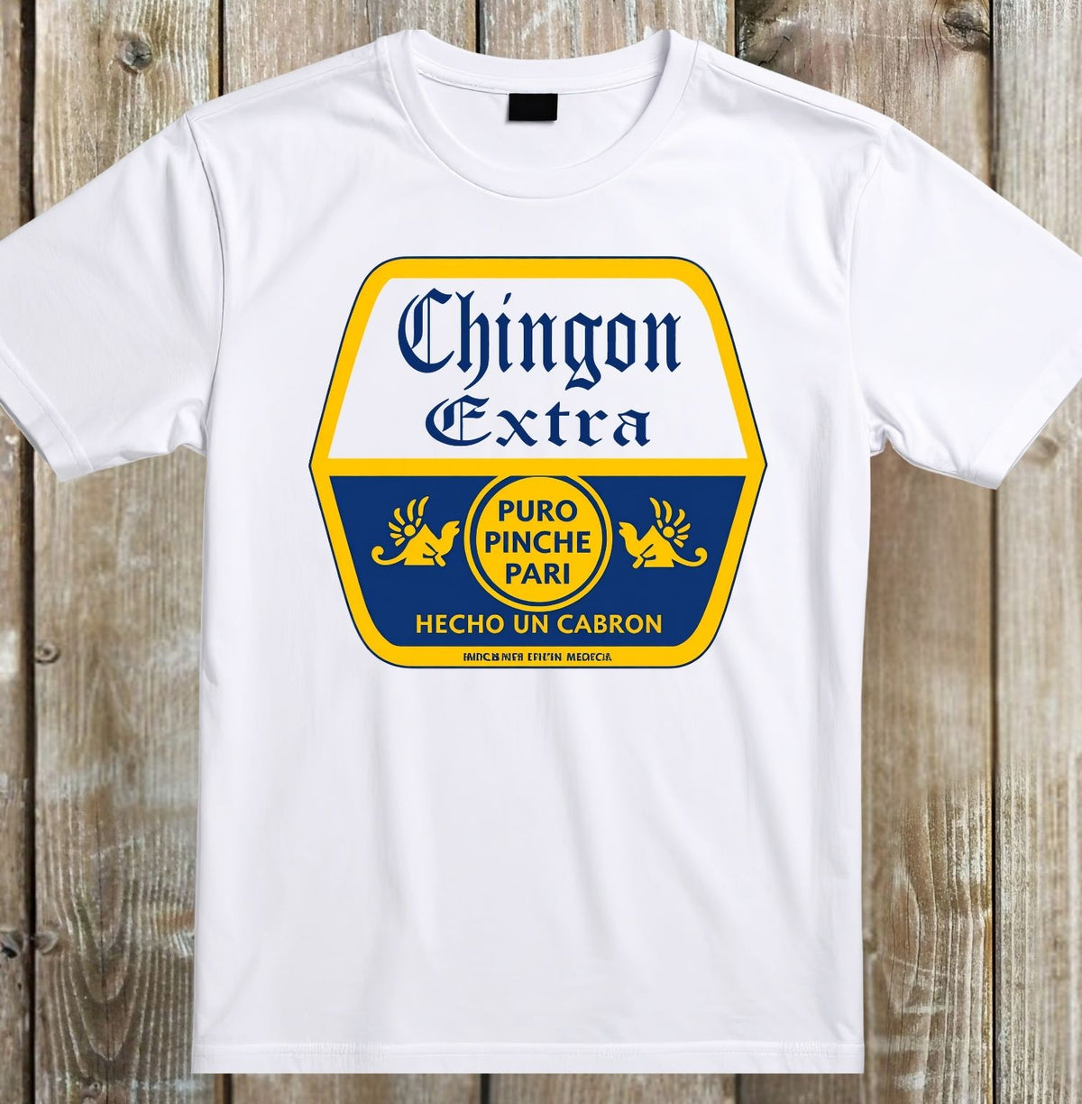 A white short-sleeve crewneck t-shirt laid flat on a rustic wooden plank background, featuring a large graphic print of the Chingon Extra beer label in blue and yellow.