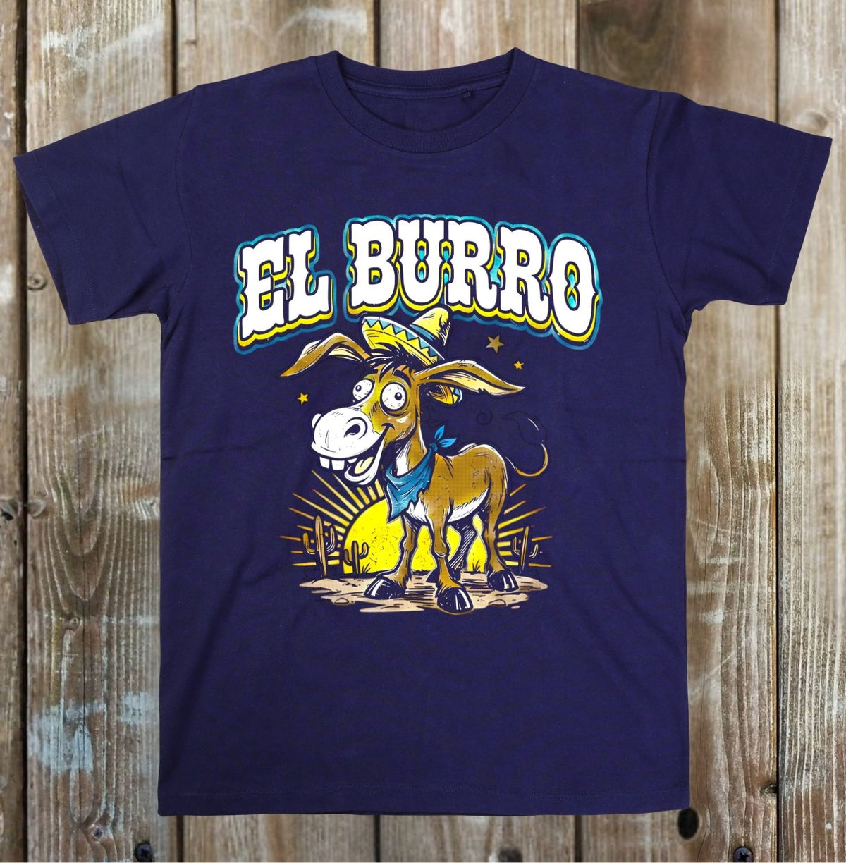 A navy blue short-sleeve t-shirt featuring a cartoon graphic of a donkey wearing a sombrero and blue bandana, with the text 'EL BURRO' in white with a blue outline, displayed flat against a rustic wooden plank background.