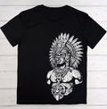 A black short-sleeve t-shirt with a large white graphic print of a detailed Aztec-style warrior wearing a feathered headdress, laid flat on a white wood plank background.