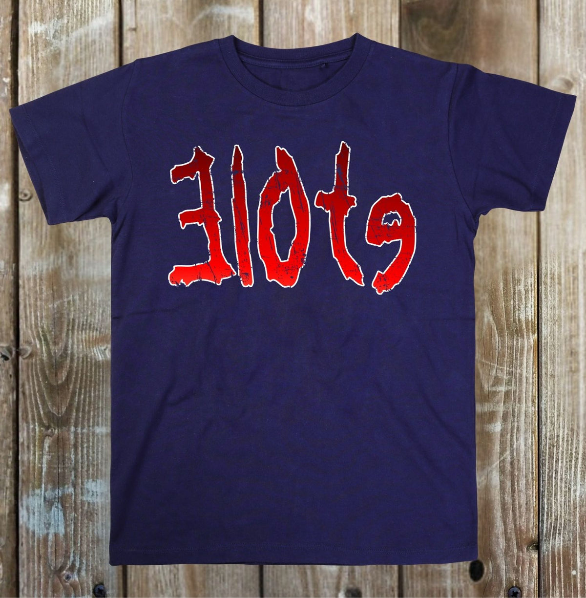 A navy blue short-sleeve t-shirt with the word 'slots' printed across the chest in a red, stylized font with a white outline, displayed flat against a rustic wooden plank background.