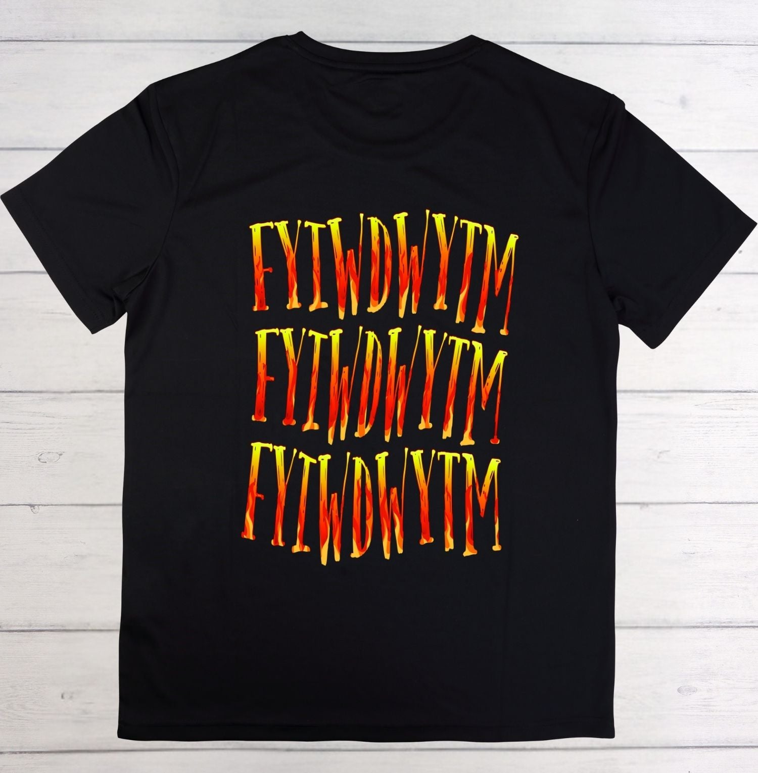 Black t-shirt with red and yellow text on a wooden surface