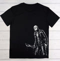 A black short-sleeve t-shirt with a white distressed graphic of Jason Voorhees holding a knife, displayed flat against a rustic wooden plank background.