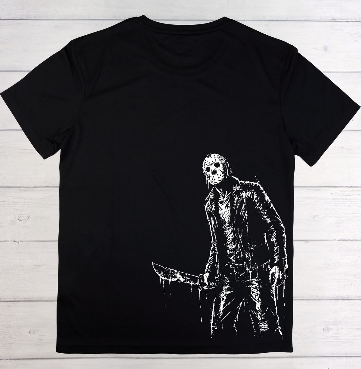 A black short-sleeve t-shirt with a white distressed graphic of Jason Voorhees holding a knife, displayed flat against a rustic wooden plank background.