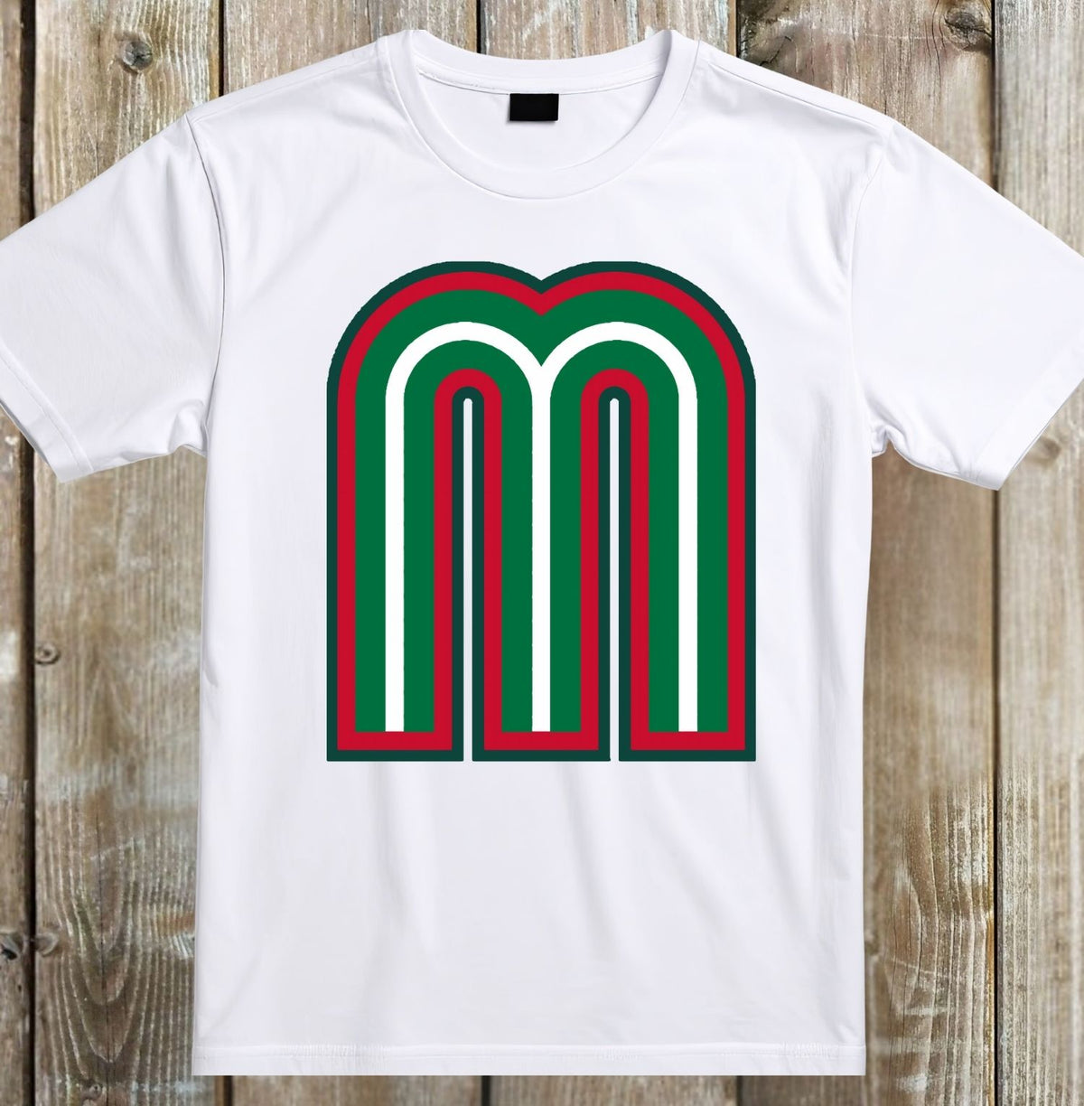 A white short-sleeve crewneck t-shirt featuring a large graphic letter 'M' on the chest with red, green, and white stripes, laid flat on a rustic wooden plank background.