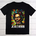 A black short-sleeve crewneck t-shirt laid flat on a white wood plank background, featuring a colorful graphic of a screaming clown face with rainbow-colored hair and the word 'MADENESS' printed below in white.
