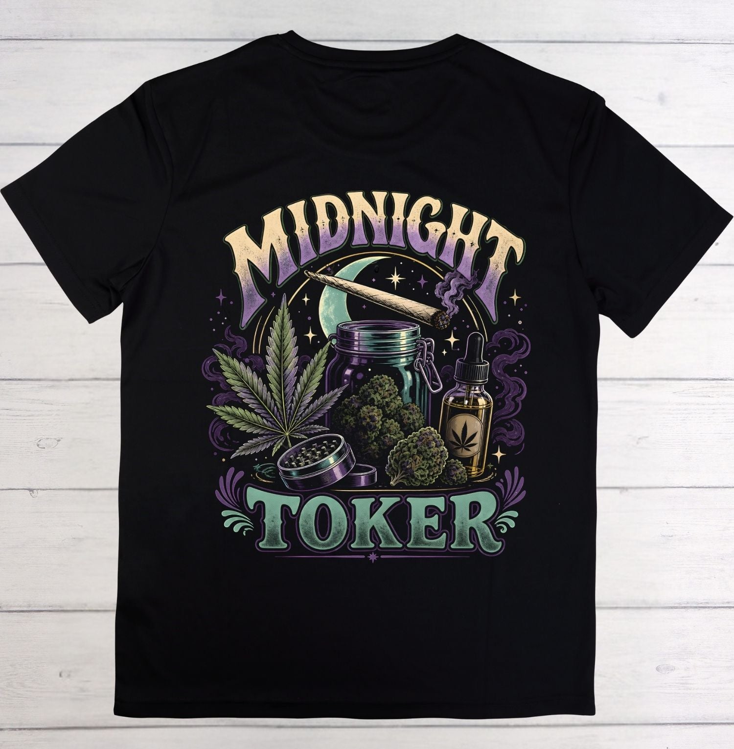 A black short-sleeve crewneck t-shirt laid flat on a white wood plank background. The front features a large graphic print with the words 'MIDNIGHT TOKER' in stylized purple and green lettering, surrounded by illustrations of a cannabis leaf, a rolling machine, a jar, a dropper bottle, and a moon.