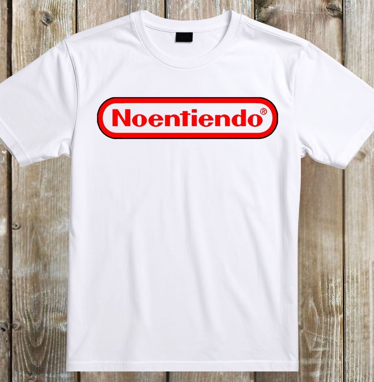 A white short-sleeve crewneck t-shirt featuring a parody graphic of the classic Nintendo logo, with the word 'Noentiendo' in red inside a red-bordered white oval, laid flat on a rustic wooden plank background.