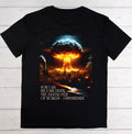 A black short-sleeve t-shirt laid flat on a light wood background, featuring a large graphic print of a nuclear mushroom cloud over a burning industrial landscape, with the text 'NOW I AM BECOME DEATH, THE DESTROYER OF WORLDS - OPPENHEIMER' printed below.