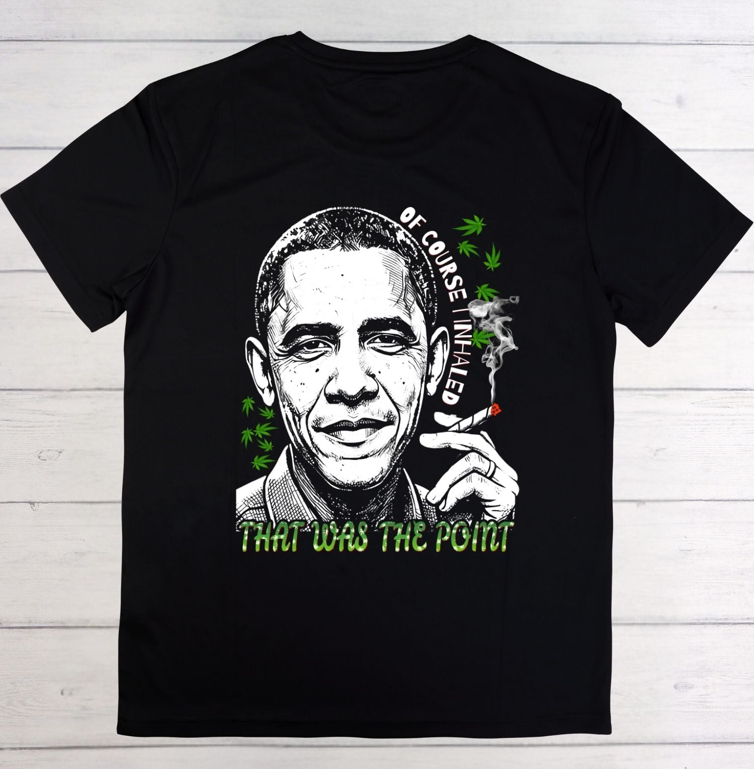 A black short-sleeve t-shirt with a graphic print of Barack Obama smoking a joint, featuring green cannabis leaves and the text 'OF COURSE I'M HIGH' and 'THAT WAS THE POINT'.