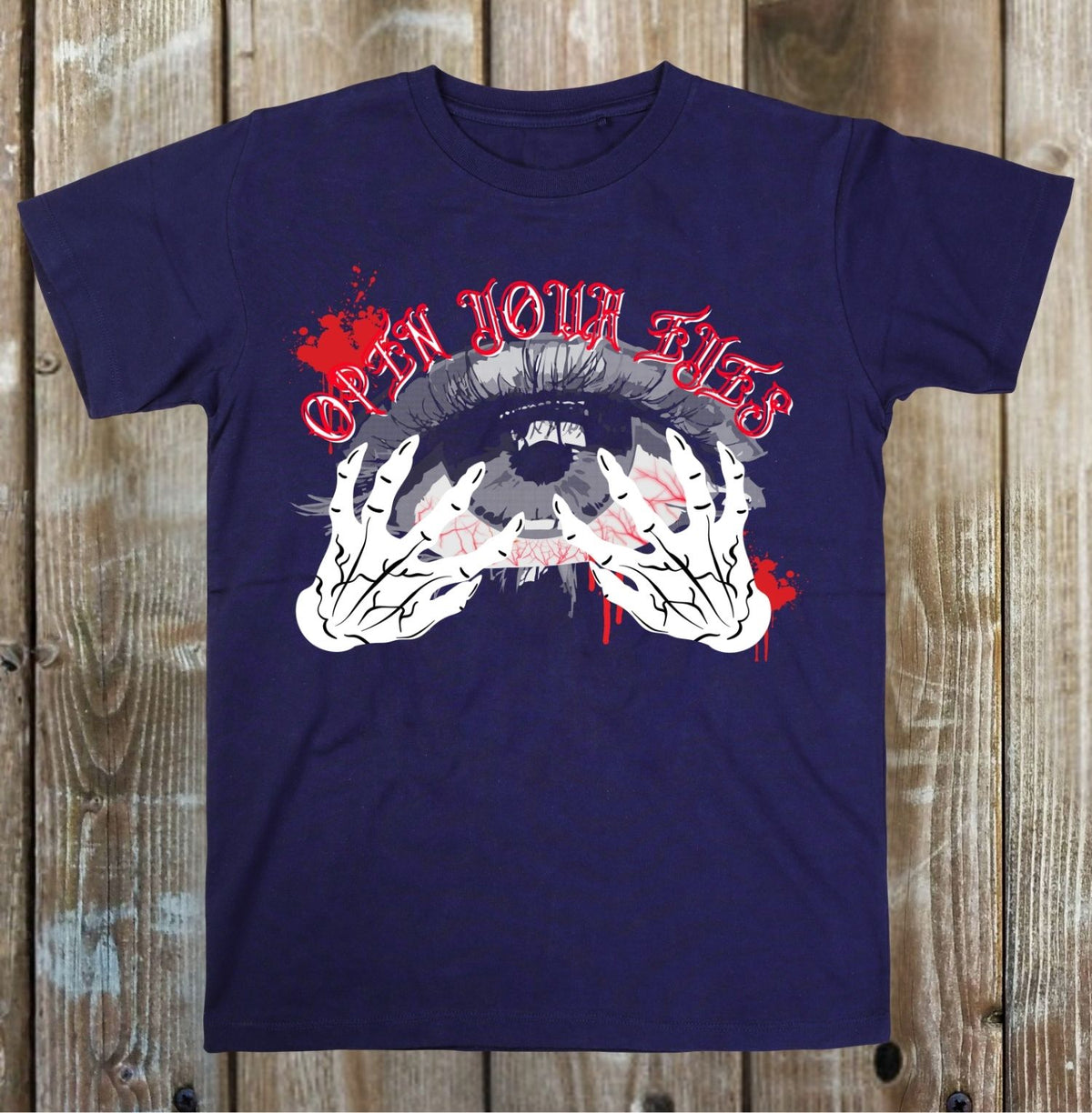A navy blue short-sleeve t-shirt with a graphic print of a screaming face, clawed hands, and the text 'OPEN YOUR EYES' in red, displayed flat against a rustic wooden plank background.