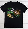 A black short-sleeve t-shirt with a detailed graphic print on the front, laid flat on a white wood plank background. The graphic features the text 'PUSH THE SPIRIT' in green and white, alongside a surreal illustration of a winged figure, a woman, and cannabis leaves.