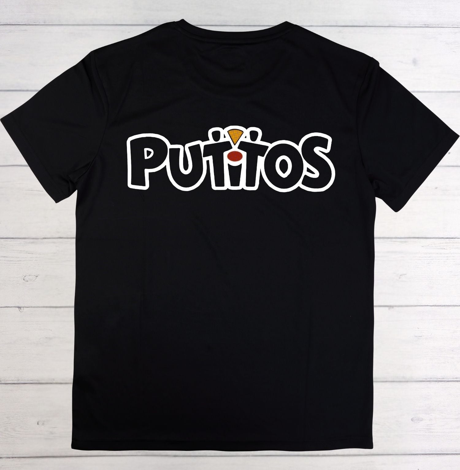 A black short-sleeve t-shirt laid flat on a white wood plank background, featuring the word 'PUTITOS' printed across the chest in white bubble letters with a small yellow and red graphic above the 'I'.