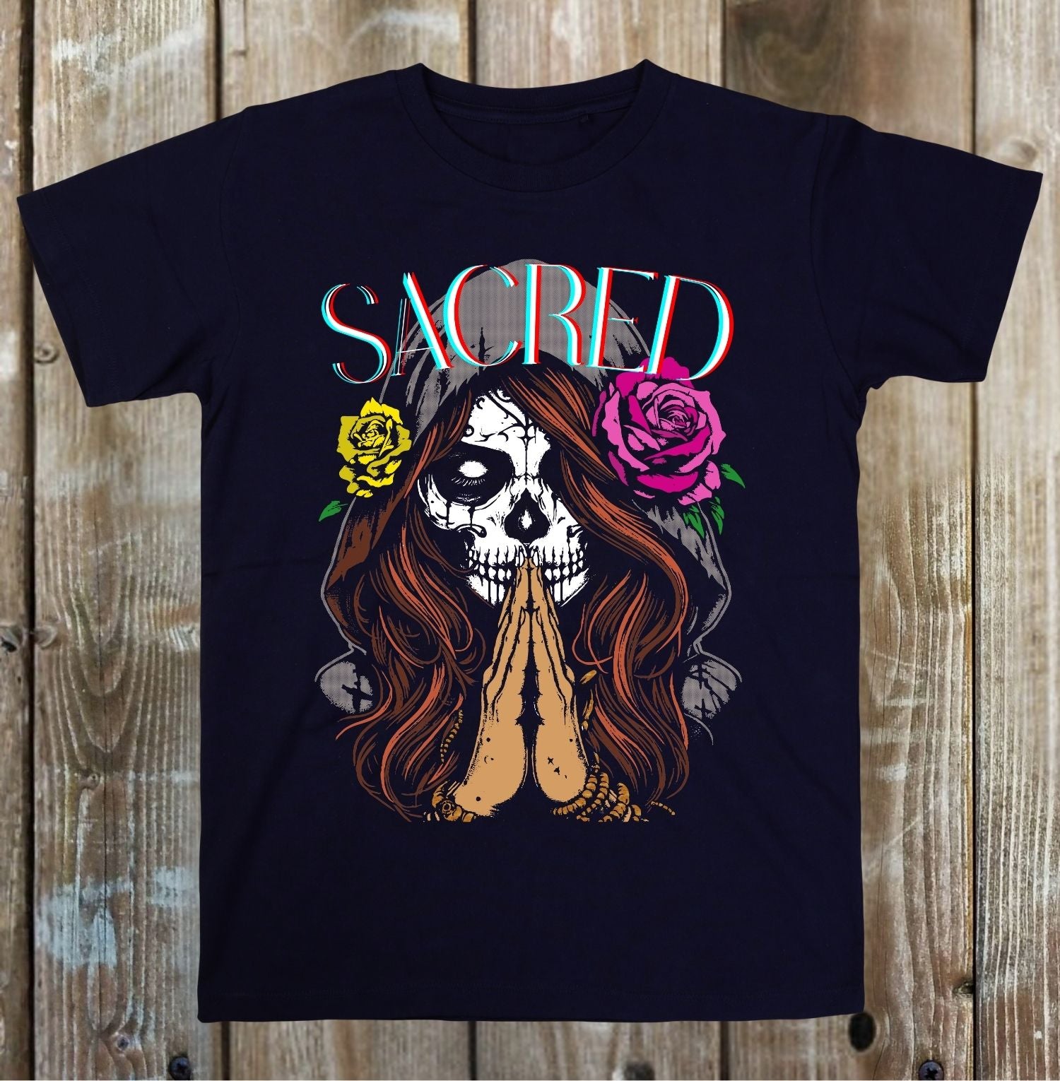 Black t-shirt with a graphic design of a skull with flowers and 'SACRED' text on a wooden background