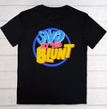 A black short-sleeve t-shirt laid flat on a white wood plank background, featuring a colorful retro graphic on the chest that reads 'SAVED BY THE BLUNT' in blue, pink, and yellow.