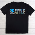 Black t-shirt with 'SEATTLE' printed in colorful letters on a wooden surface