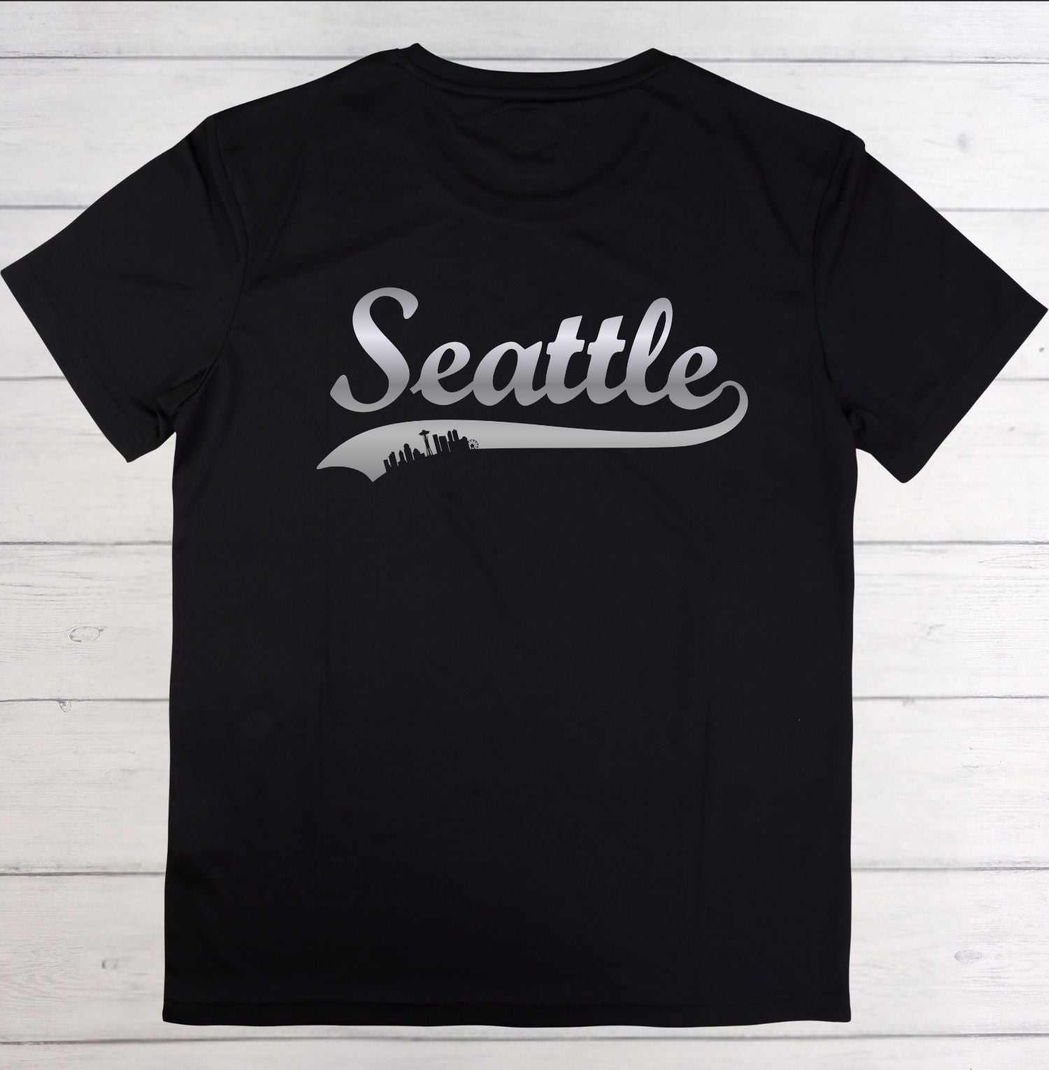 Black t-shirt with 'Seattle' printed on it against a white wooden background