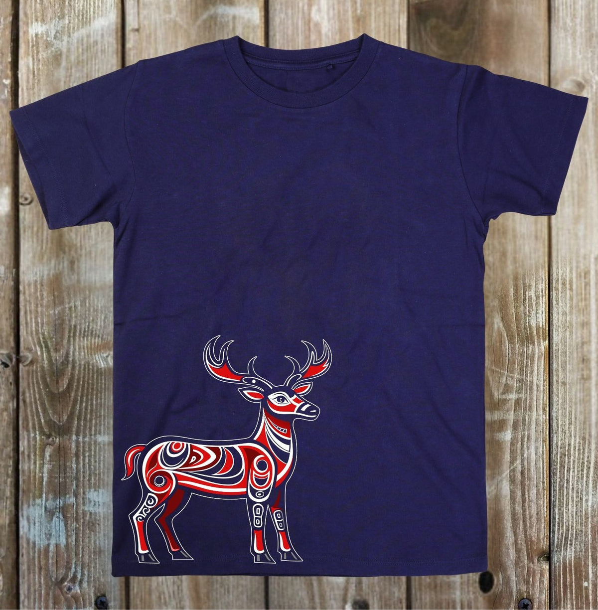 A navy blue short-sleeve t-shirt featuring a stylized red, white, and black deer graphic on the front, laid flat against a rustic wooden plank background.