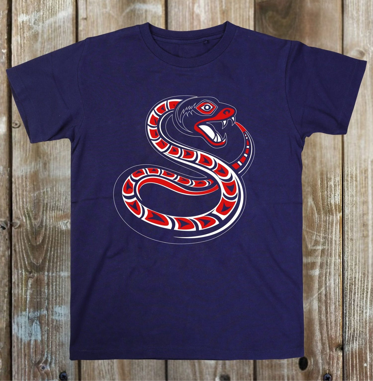 A navy blue short-sleeve t-shirt with a red, white, and black snake graphic on the front, displayed flat against a rustic wooden plank background.