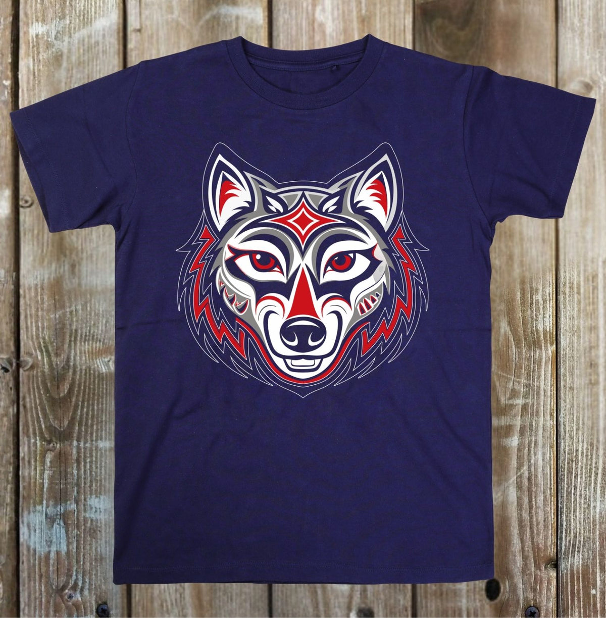 A navy blue short-sleeve t-shirt with a stylized, geometric wolf head graphic in red, white, and blue, laid flat on a rustic wooden plank background.