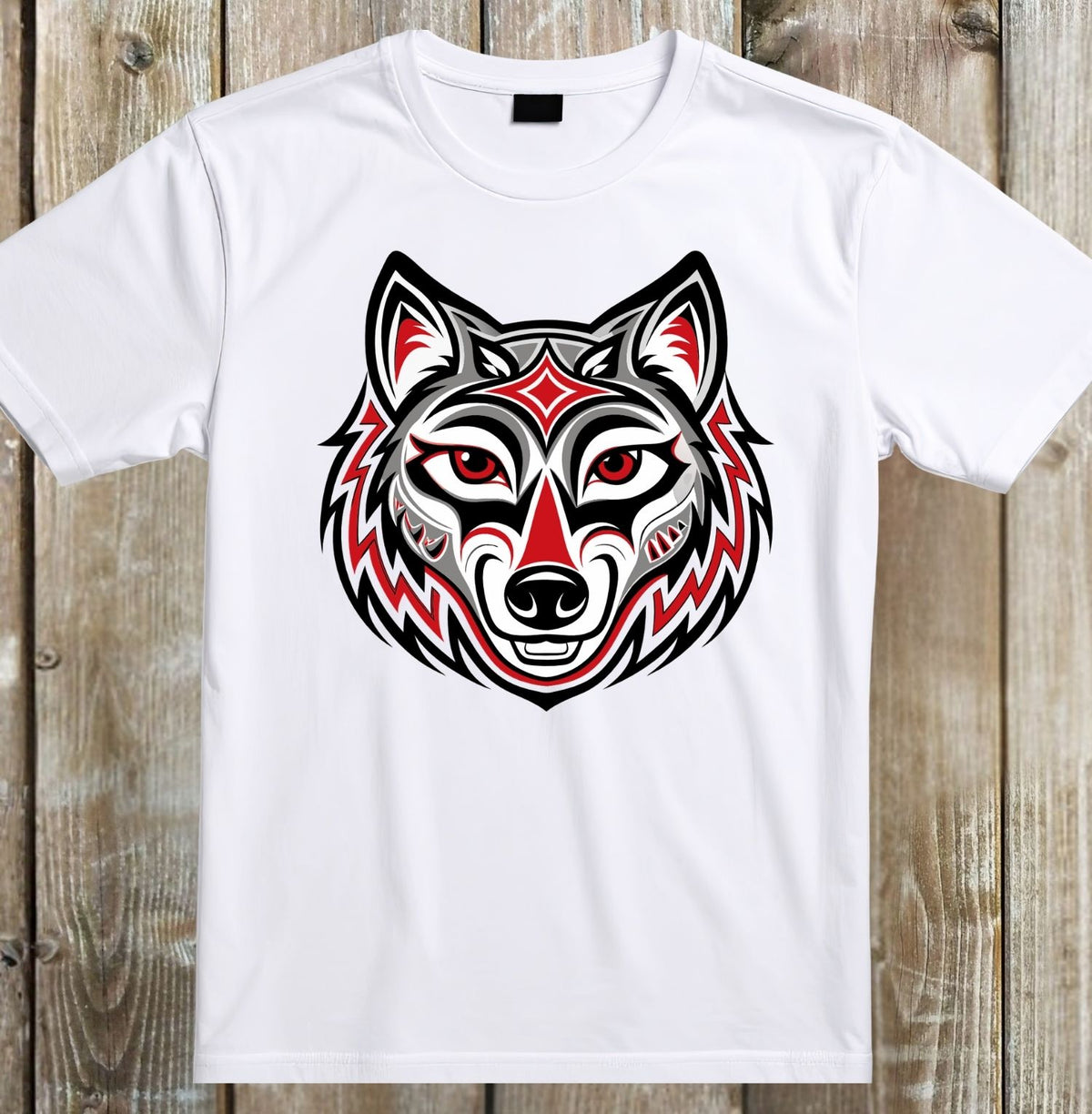A white short-sleeve crewneck t-shirt featuring a stylized graphic of a wolf head in a Native American-inspired pattern with red, black, and white details, displayed flat against a rustic wooden plank background.