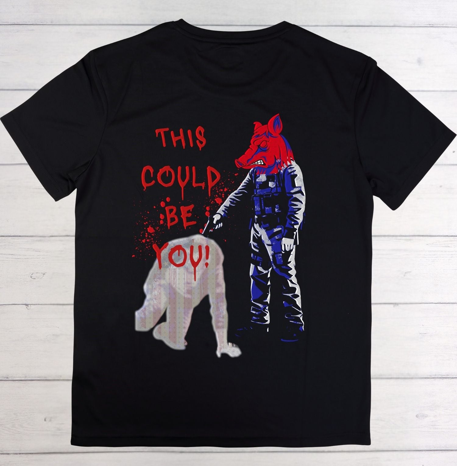 Black t-shirt with graphic design of a person holding a bear and text 'THIS COULD BE YOU!' on a wooden background