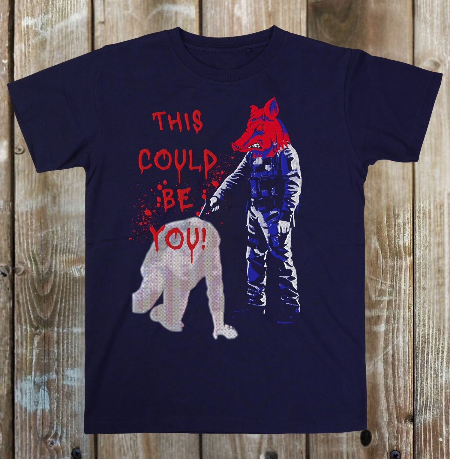 Navy blue t-shirt with graphic design of a person in a suit holding a bear and text 'THIS COULD BE YOU!' on a wooden background.