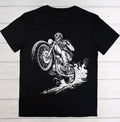 A black short-sleeve crewneck t-shirt laid flat on a light gray wood plank background, featuring a detailed white graphic print of a skeleton riding a motorcycle.